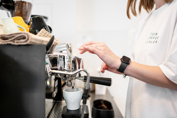 Barista in white shirt operates espresso machine, pouring coffee into cup. Colorful mugs and tools...