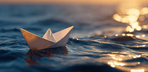 Paper boat gently floats on shimmering ocean at sunset, creating serene and peaceful scene