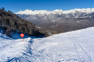 A breathtaking snowy mountain slope with ski tracks left by skiers.