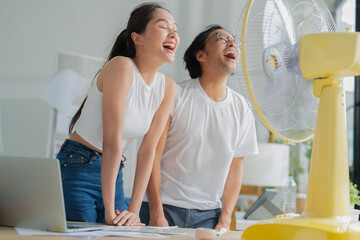 happiness cheerful asian partner smile feel the wind from table fan fight the hot air condition...