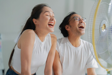 happiness cheerful asian partner smile feel the wind from table fan fight the hot air condition...