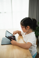 Young girl using tablet at home with curiosity, engaging in learning and digital exploration...
