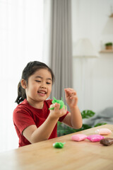 Happy child engaging in creative play with colorful modeling clay at home, fostering imagination...
