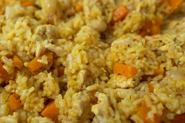 A vibrant, close-up shot of a plate of Plov, a traditional Central Asian rice pilaf. The dish is presented on a clean white plate with a marble background, focusing on the texture and golden-yellow 