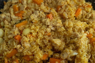 A close-up of finished Plov, showing the fluffy golden rice grains, tender chunks of chicken, and soft orange carrots. This detailed shot captures the final dish, ready to be served, making it ideal f