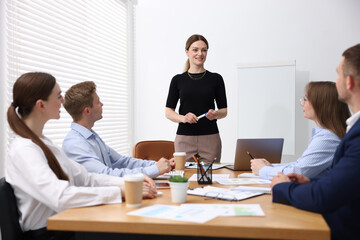 Business coach giving presentation to group of people in office