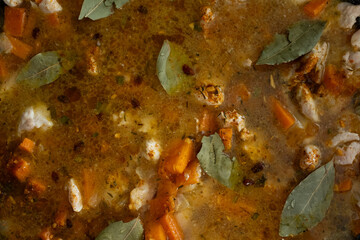 A close-up, high-angle shot of rice, spices, and other ingredients submerged in a rich broth during...