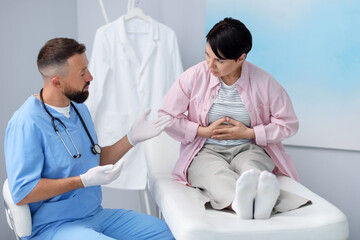 Obraz premium Gastroenterologist consulting patient with stomach pain in clinic