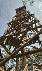 Fototapeta premium Wooden observation tower in the forest with spiral stairs, rustic architecture and scenic outdoor adventure structure. 