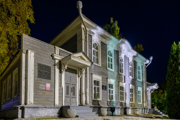 A beautifully illuminated wooden mansion at night with classic architecture.