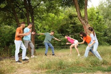 Team building. Group of happy people playing spider web game outdoors
