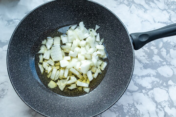 A flat lay featuring chopped white onions, a kitchen knife, and a specialized julienne peeler on a dark background. This image highlights food preparation and tools, key elements for cooking Plov. 