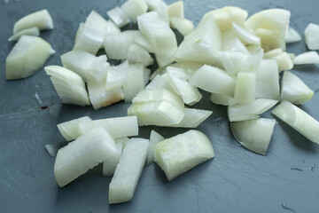 Close-up of diced white onions on a gray board. Fresh, raw, and ready for cooking Plov. Essential ingredient, food prep detail. Ideal for recipe blogs and cookbooks showcasing basic culinary steps and
