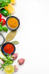 Food and spice background with herbs, turmeric, dried herbs, chili powder and kitchen utensils, white table, top view