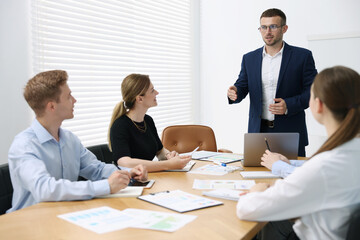 Business coach giving presentation to group of people in office