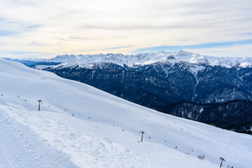 Snowy mountain slopes, a view from above of ski trails and cable cars.