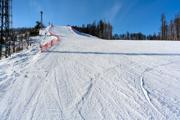 Steep ski slope with red restrictive net against the backdrop of picturesque Ural Mountains landscape.
