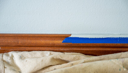 Interior painting project in a home with careful taping along the wooden trim in a light and airy room