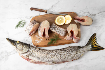 Whole peeled fish and prepared steaks of fresh pike with spices and lemon slice for cooking on...
