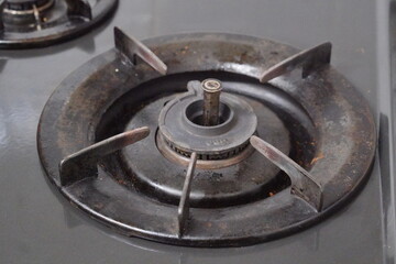 Close-up of old rusty gas stove burner with visible stains and worn metal parts, symbolizing home...