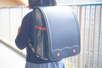 Elementary school student carrying a traditional Japanese navy blue randoseru backpack with red flower decorations, symbol of childhood, education, and school life in Japan