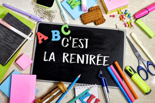 School supplies arranged around a blackboard with a word french C'est La Rentrée symbolizing the start of the school year