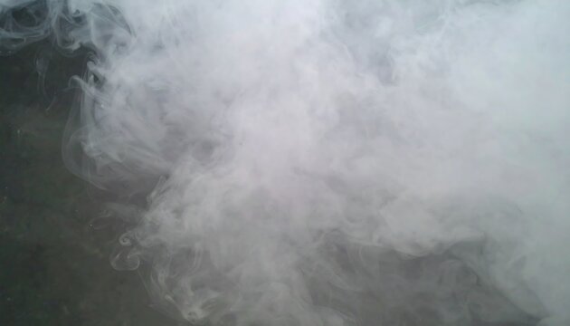 A captivating display of ethereal white smoke, gracefully swirling and diffusing over a dark gray backdrop.