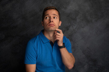 Man in blue polo shirt thinking against dark background