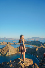 Back view of a young Asian woman enjoying holiday and scenery at Padar mountain hill, Labuan Bajo.