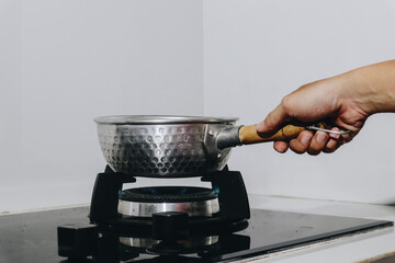 A Hand Holding a Stock Pot on a Stove, Capturing the Essence of Culinary Creativity and Kitchen...
