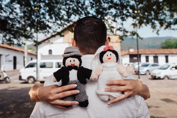 couple holding some knitted cloth dolls of bride and groom