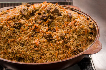 Traditional Uzbek plov pilaf, served in a large pot, showcasing vibrant rice, tender meat, and...