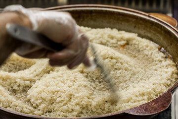 Traditional Uzbek rice dish being stirred in a large pot, pilaf, showcasing the cooking process and...