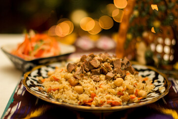 Traditional pilaf Uzbek dish featuring flavorful rice, tender meat, and chickpeas served on a decorative plate with vibrant colors and rich textures, showcasing cultural heritage. Copy space, menu