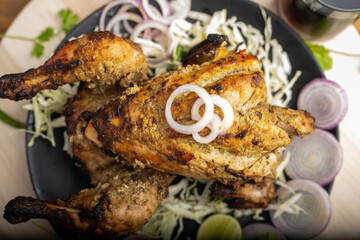 Crispy delicious whole chicken tandoori with vegetables or salad served in plate 