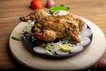 Crispy delicious whole chicken tandoori with vegetables or salad served in plate 