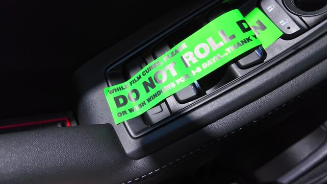 Green sticker on the car door says, While film cures do not roll down or wash windows for 3 to 5 days after installation of tinting film on the car glass. Protective UV film and tint on the car glass.