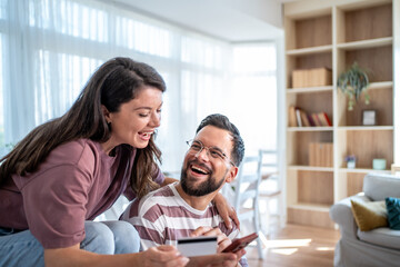 Obraz premium Happy couple making online payment with credit card at home