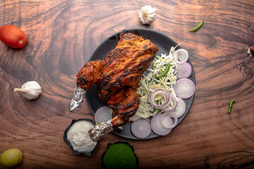 Crispy delicious whole chicken tandoori with vegetables or salad served in plate 