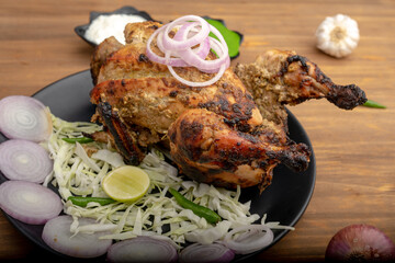 Crispy delicious whole Afghan  chicken tandoori with vegetables or salad served in plate 