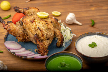 Crispy delicious whole Afghan  chicken tandoori with vegetables or salad served in plate 