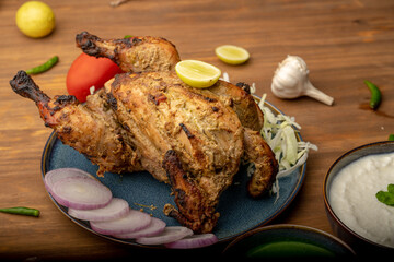 Crispy delicious whole Afghan  chicken tandoori with vegetables or salad served in plate 