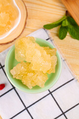 Yellow Rock Sugar Candy Crystals in Bowl with Fresh Mint Leaves on Wooden Table