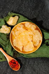 Raw Yellow Rock Sugar Crystals in Wooden Bowl Natural Sweetener Ingredient on Dark Stone Background