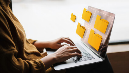 Organizing Digital Files A Person Using a Laptop with Holographic Folders Displayed on the Screen for Efficient Data Management and Storage Solutions