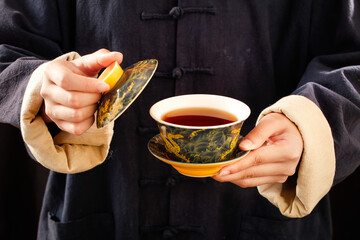 Traditional Chinese Black Puerh Tea Ceremony with Ornate Golden Tea Cup and Saucer