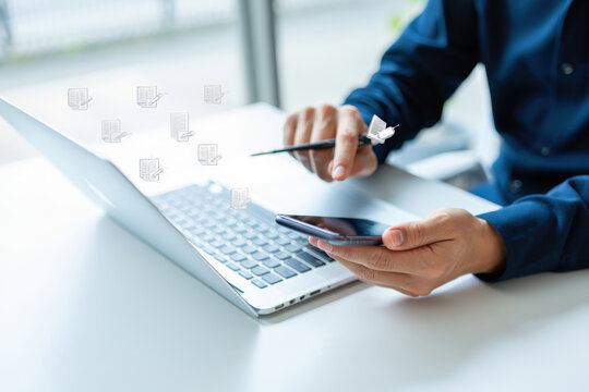 Person Using Laptop and Smartphone with Digital Document Icons, Representing Document Management and Workflow Automation in Modern Business Environment