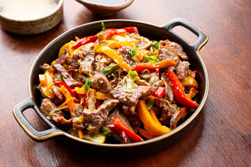 Beef stir fry in a frying pan top view, Asian meat with vegetables on a table
