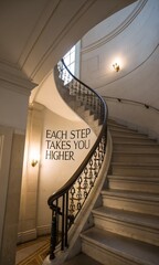 Obraz premium Elegant Spiral Staircase with Inspirational Wall Quote and Lighting