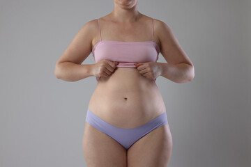 Liposuction. Woman in underwear on grey background, closeup